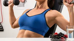 Žena cvičí tlaky s jednoručkami v posilňovni po rozcvičke