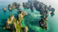 Letecký pohľad na vápencové ostrovy a člny v smaragdovej zátoke zálivu Ha Long, Vietnam